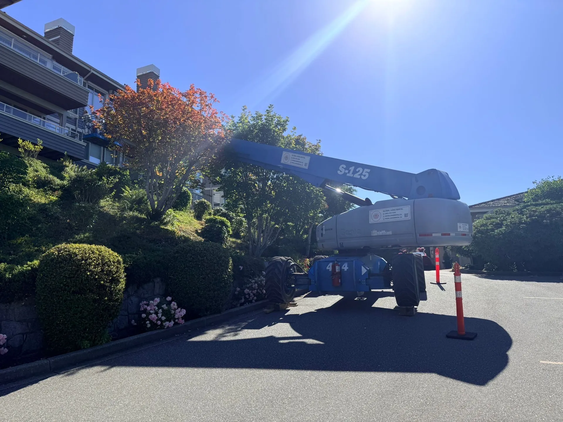 Global Lions Rental boom lift working beside a residential building