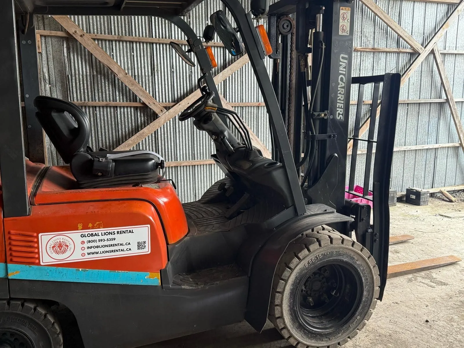 Global Lions Rental orange forklift inside a storage shed